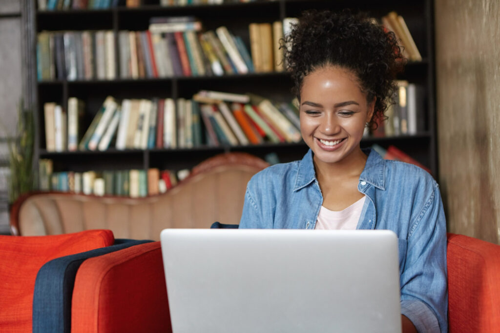 A woman sitting on a couch, focused on her laptop, representing the unique features of Expert assignment help.